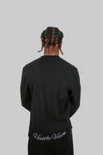 Load image into Gallery viewer, Person wearing a black sweatshirt with 'Hustle Vision' text on the back against a light blue background

